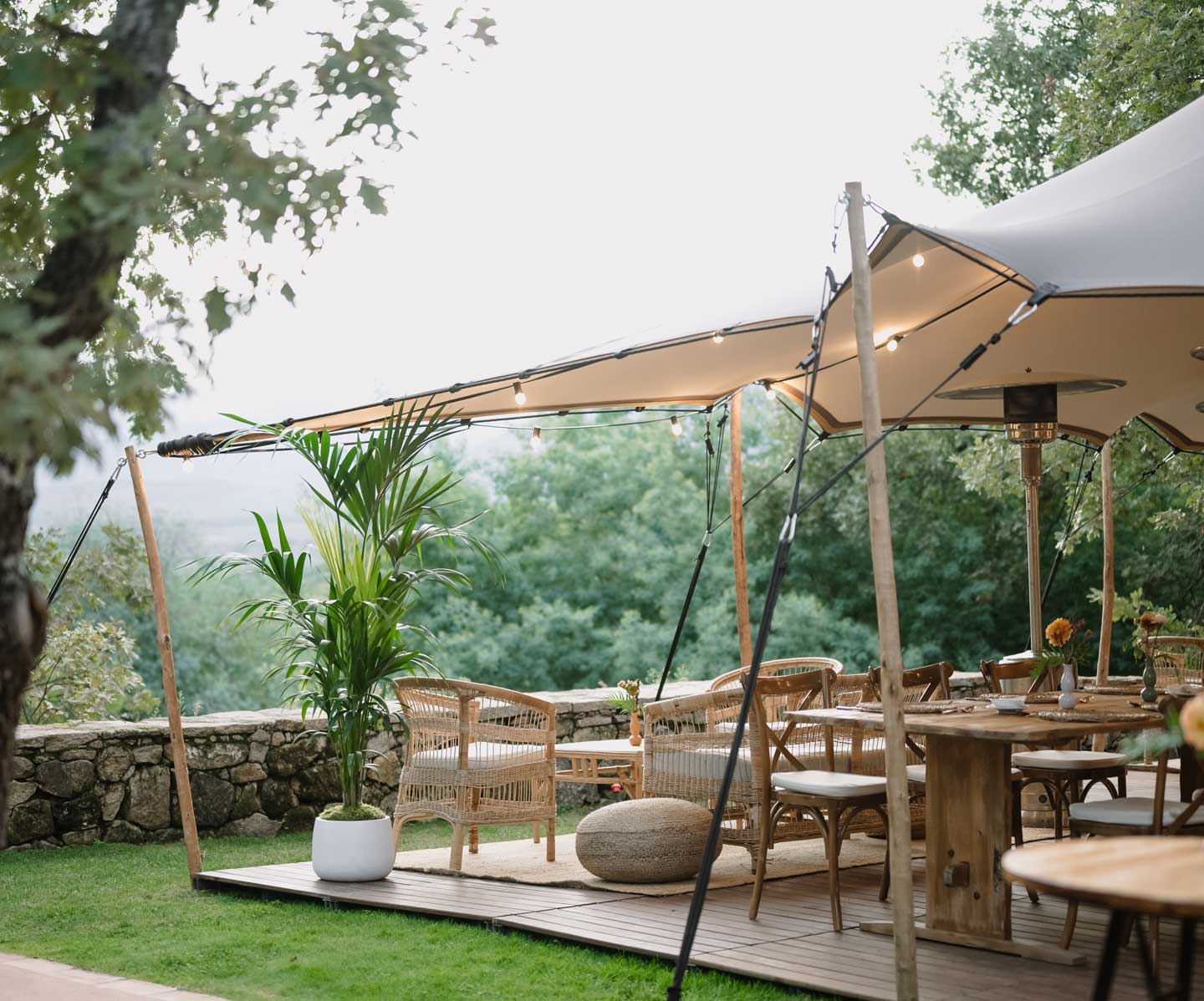 Mesas y sillas de mimbre bajo una carpa en el campo